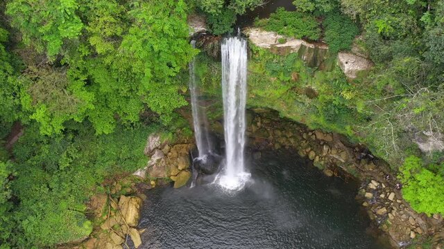 Aerial: tall Mexican Misol-Há waterfall cascading over canyon, arc shot