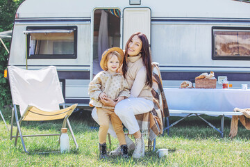 Family mother and daughter in nature relax traveling in a trailer, a motor home