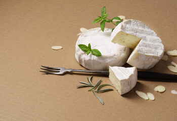 camembert cheese with nuts, fork and rosemary on cardboard.