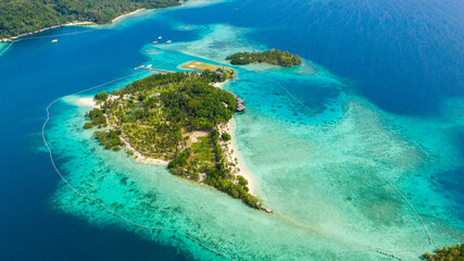 Island with beautiful beach, palm trees by turquoise water view from above. Malipano island, Philippines, Samal.