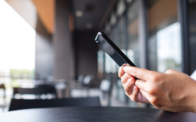 Closeup image of a hand holding and using mobile phone