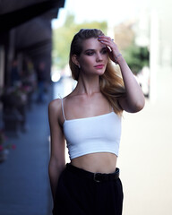 Blonde outdoors in white top, black pants and heels