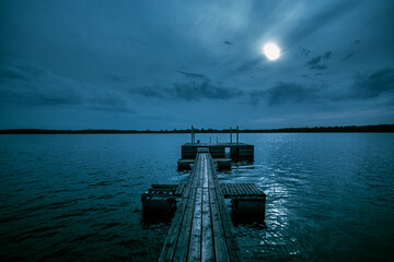 A pier on the lake for fishing. Dramatic, gothic and scary lonely atmosphere.