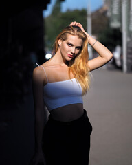 Blonde outdoors in white top, black pants and heels