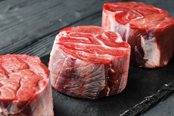 Raw beef fillet steaks on black wooden table