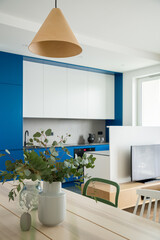 Wooden dining table next to modern white and blue kitchen