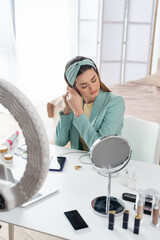 young beauty blogger preparing for record near phone holder and containers with cosmetics.