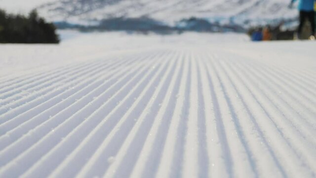 Groomed snow on a ski hill. Fresh Corduroy Pattern on Snow. Corduroy snow at winter ski resort, ski slopes are prepared trail. Freshly groomed run and track with funicular and prepared track.