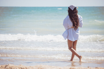 A black girl walking on the beach while she is wearing sunglasses enjoying a sunny day. Summer...