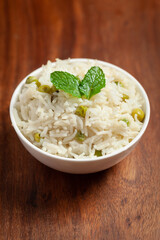 Close-up of Indian Basmati steamed Rice or matar (Pea) pulao or Pulav garnished with fresh green mint leaf