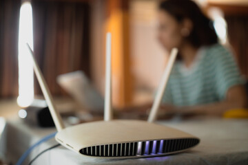 A woman is working at home using a modem router, connecting the Internet to her laptop.