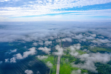 Road with cars, low clouds, shoot from a drone. Beautiful landscape from above