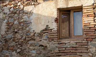 Wood window in an old facade. Damaged brick wall.