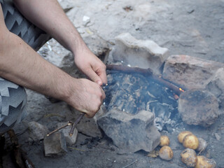the process of lighting a fire in the forest during a picnic. men's hands break a branch