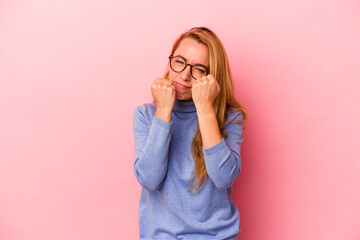 Caucasian blonde woman isolated on pink background throwing a punch, anger, fighting due to an argument, boxing.