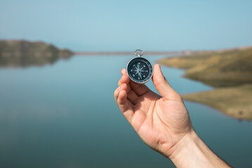 man holding compass in lake background