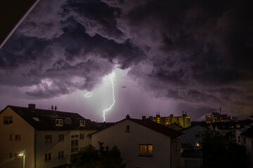 Image of lightning strike over buildings with threatening cloud formations
