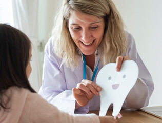 Dentist teaching little girl how to brush teeth