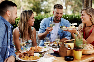 Group of Happy friends having lunch in the restaurant during a sunny summer day - 443590722