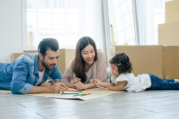 Fototapeta premium Happy family consists of caucasian handsome father, Asian beautiful mother and little cute daughter doing activitiy, playing together, drawing and painting as leisure and hobby during holiday at home.