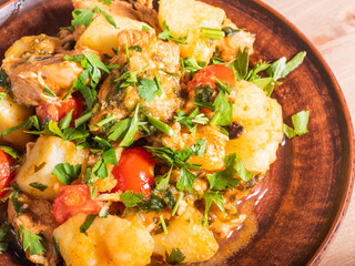 Homemade stew of chicken, potatoes and tomatoes in a plate, close-up