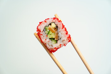 sushi sticks keep roll with caviar, fish, rice and avocado on white background