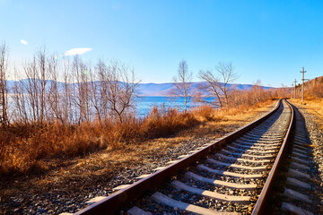 Fototapeta premium Circum Baikal railway running along the shore of Lake Baikal on an autumn sunny day with a yellow landscape around