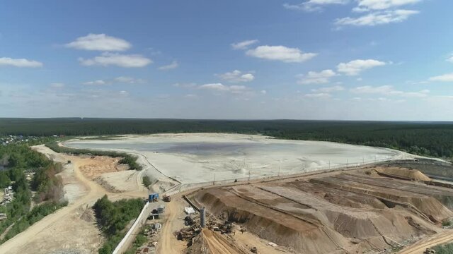 Aerial view of Huge sand dumps from a gold mine. Near the forest, the village and the river. A summer sunny day

