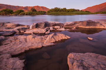 Fototapeta na wymiar Landscape with river and mountains in the blue hour after sunset: orange river at the border between Namibia and South Africa