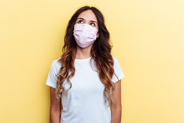 Young mixed race woman wearing a protection for virus isolated on yellow background dreaming of...