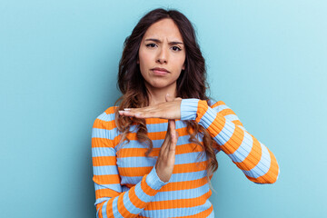 Young mexican woman isolated on blue background showing a timeout gesture.