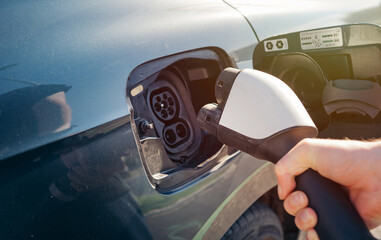 Man hand is holding Electric car charging connect to elecric car on charge station, Electric...