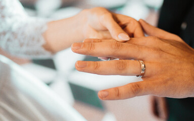 Obraz premium Closeup of putting a wedding ring onto the bride finger. Couple exchanging wedding rings. High quality photo