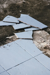 blue outdoor tiles getting ripped up to reveal concrete paving underneath, concept of demolition or...