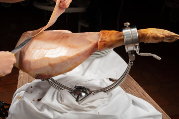  Mano con cuchillo quitando el tocino de un jamón ibérico. Hand with a knife removing the bacon...