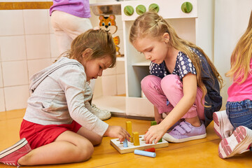 Mädchen spielen mit Bauklötzen ein Steckspiel
