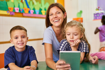 Kindergärtnerin und Kinder nutzen App auf dem Tablet