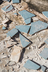blue outdoor tiles getting ripped up to reveal concrete paving underneath, concept of demolition or renovation