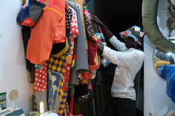 Black man choosing an african item of clothing to wear. African tailor in his sewing workshop.