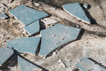 blue outdoor tiles getting ripped up to reveal concrete paving underneath, concept of demolition or renovation