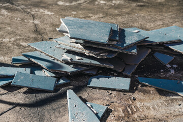 blue outdoor tiles getting ripped up to reveal concrete paving underneath, concept of demolition or...