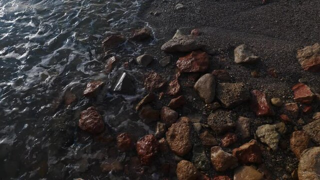 Stone pebble seashore with sea waves splashing in slow motion