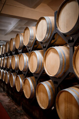 Old aged traditional wooden barrels with wine in a vault lined up in cool and dark cellar in Italy, Porto, Portugal, France