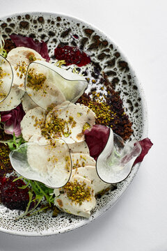 vitello tonnato of thinly sliced marinated veal on a beautiful plate, top view, tender veal dressed with creamy sauce and tuna, copy space.