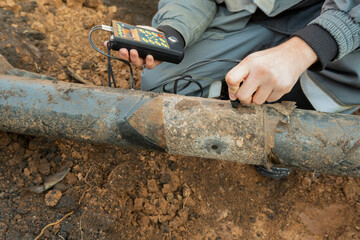 Inspection of the underground pipeline. Measurement of the pipe wall thickness. Selective focus. - obrazy, fototapety, plakaty