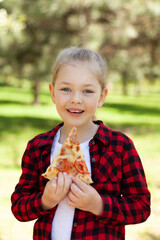 Child girl eating pizza outdoors. Delicious snacks, street food delivery.