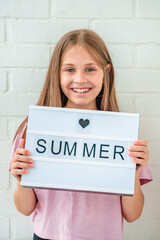 A happy little girl holds a banner with the word "summer"