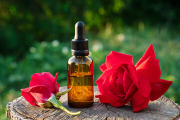 Rose essential oil or flavored water bottle. Red rose flowers.