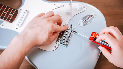 Guitar master repairing electric guitar, top view, closeup