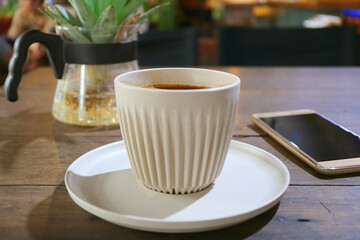 Cup of Hot Coffee on a Wooden Table with Blank Screen Smartphone in Background